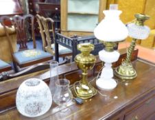 THREE EDWARDIAN OIL TABLE LAMPS, comprising: two in brass one with etched glass shade, the other