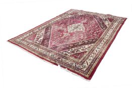 EASTERN CARPET, with diamond shaped white medallion with pendants on a red and herati field with