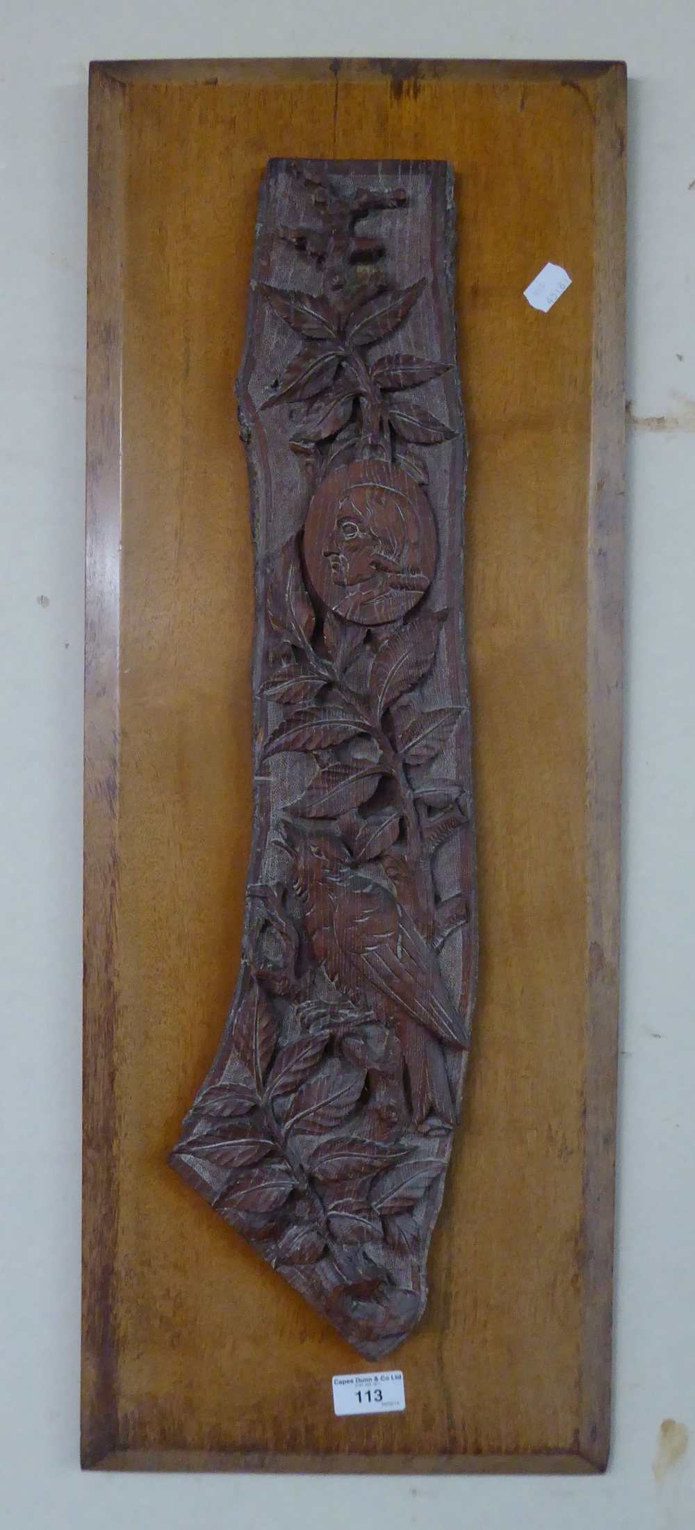 A CARVED WOOD PANEL, WITH FOLIAGE AND HEAD OF A MAN MOUNTED ON A WOODEN BACKGROUND