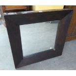 A RECTANGULAR BEVELLED EDGE WALL MIRROR IN BROAD PLAIN EBONISED FRAME