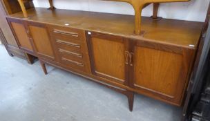 A G-PLAN DARK TEA SIDEBOARD, HAVING TWO END CUPBOARDS AND FOUR CENTRAL DRAWERS ON SHAPED SUPPORTS