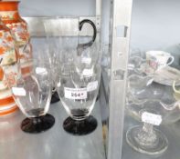 A GLASS WATER JUG WITH BLACK GLASS HANDLE AND BASE; A SET OF SIX MATCHING GOBLETS; A SET OF FOUR