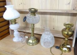 THREE EDWARDIAN OIL TABLE LAMPS, comprising: two in brass one with etched glass shade, the other