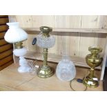 THREE EDWARDIAN OIL TABLE LAMPS, comprising: two in brass one with etched glass shade, the other