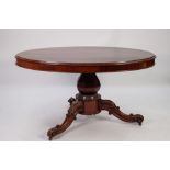 VICTORIAN CARVED AND FIGURED MAHOGANY LOO TABLE, the flame cut oval tilt top above a heavy base with