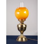 AN ADAPTED OIL LAMP WITH ORANGE GLASS GLOBE AND CLEAR GLASS FUNNEL