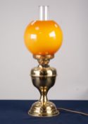 AN ADAPTED OIL LAMP WITH ORANGE GLASS GLOBE AND CLEAR GLASS FUNNEL