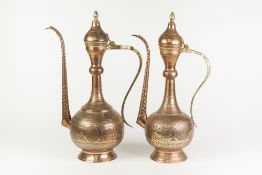 TWO MIDDLE EASTERN ENGRAVED COPPER AND BRASS PEDESTAL COFFEE POTS OR EWERS, each of typical form