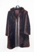 LADY'S LUSTROUS BROWN BEAVER LAMB FULL LENGTH COAT, with revered collar, brown leather trim to the