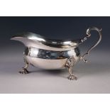 PRE-WAR SILVER SAUCE BOAT OF GEORGIAN DESIGN with everted cut rim and scroll handle, standing on