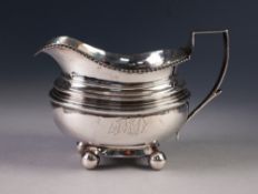 GEORGE III NEWCASTLE SILVER CREAM JUG with gadrooned rim and angular handle, standing on four ball