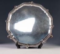EARLY 20th CENTURY SILVER SALVER with shaped shell work border, standing on three claw feet,