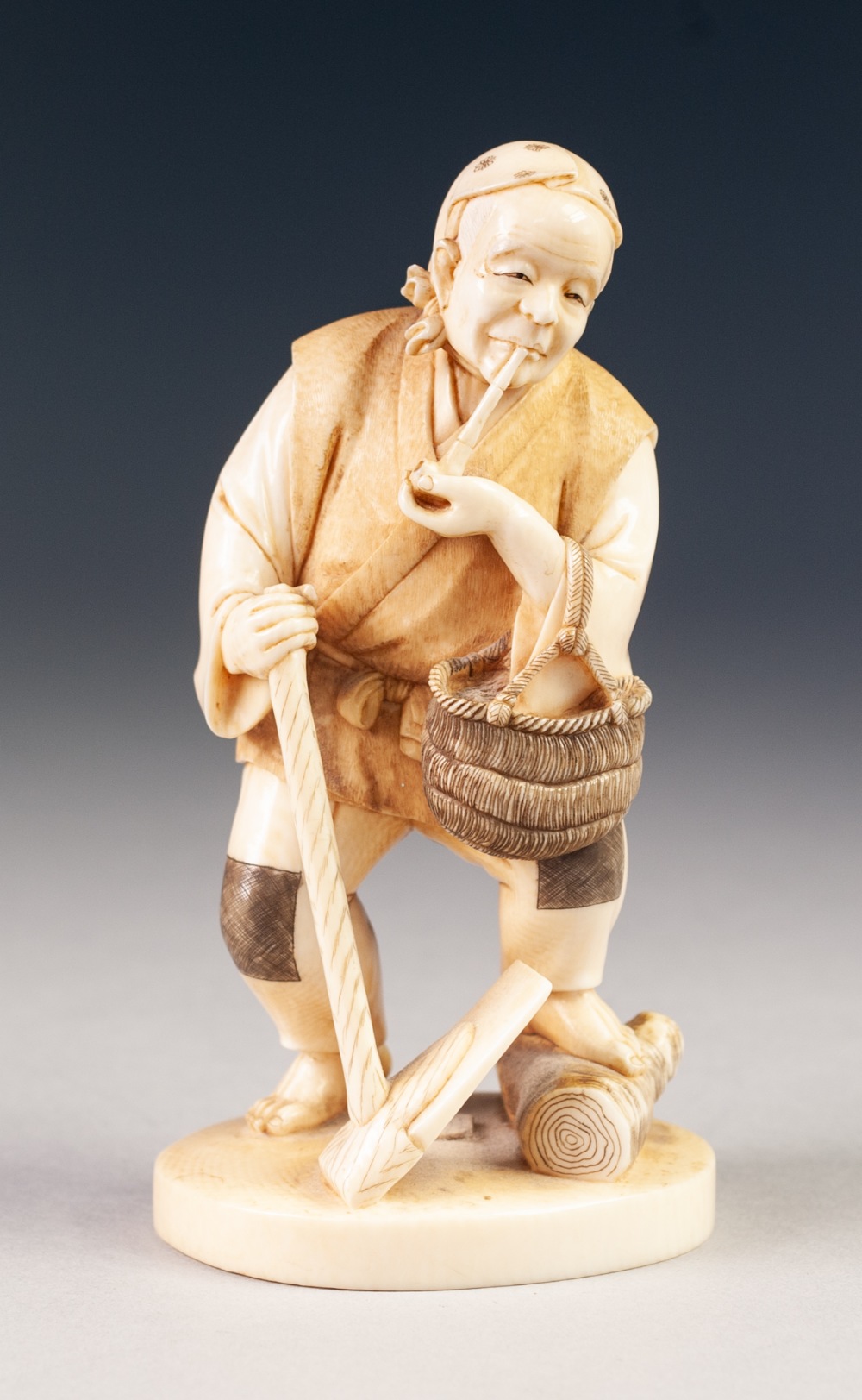 A GOOD JAPANESE MEIJI PERIOD ONE PIECE CARVED IVORY FIGURE of a peasant male, standing smoking a