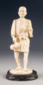 JAPANESE MEIJI PERIOD CARVED SECTIONAL IVORY OKIMONO, modelled as a man, standing, carrying a double