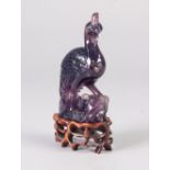 A TWENTIETH CENTURY CHINESE CARVED AMETHYST QUARTZ PHOENIX, on openwork wooden stand, 4 1/2" (11.