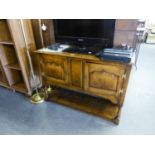 A GOOD QUALITY DISTRESSED OAK LOW SIDEBOARD, TWO PANEL DOORS ABOVE AN OPEN SECTION, WITH BRASS 'H'