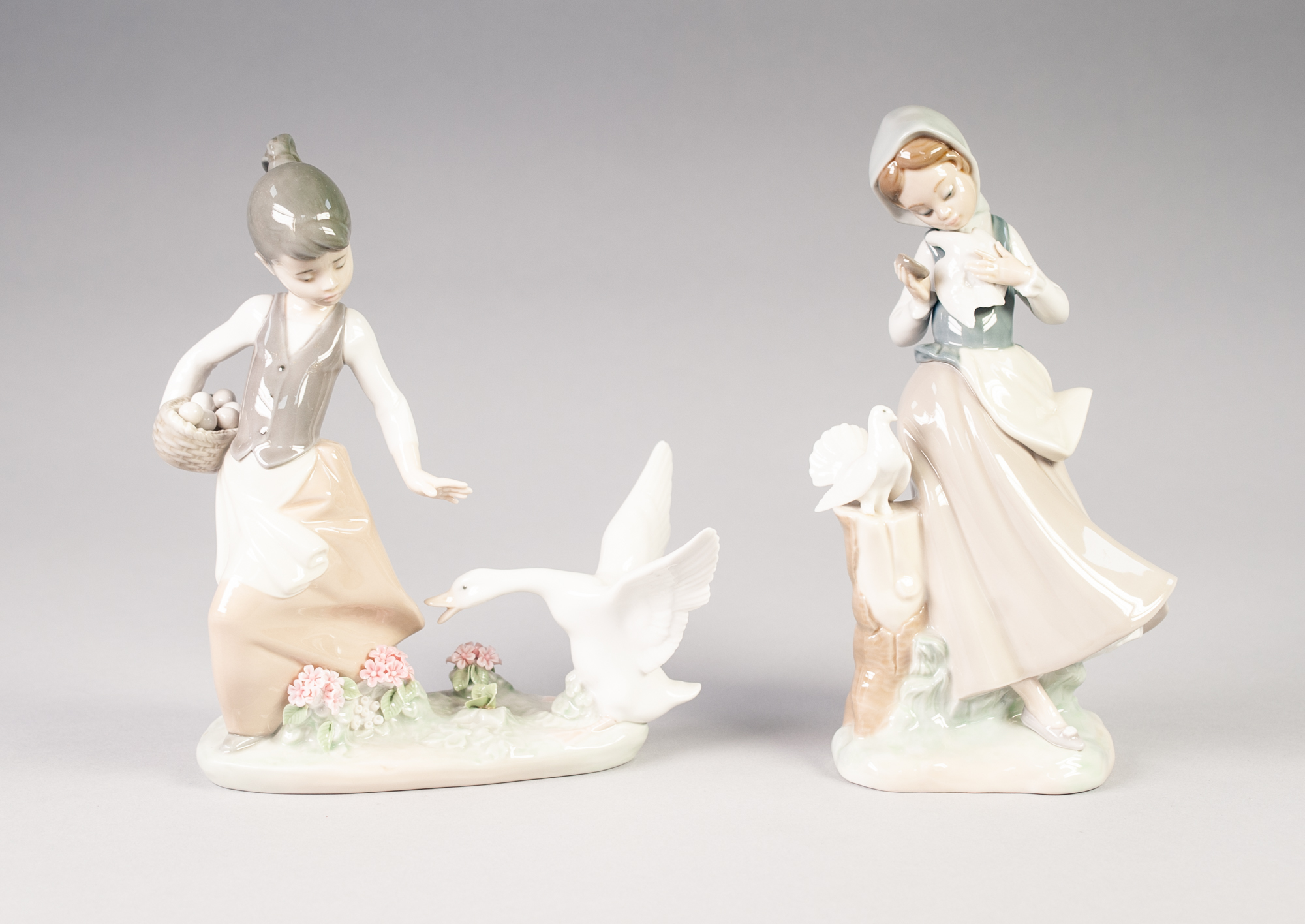 TWO LLADRO PORCELAIN GROUPS OF YOUNG GIRLS AND BIRDS, one modelled standing beside a tree stump with