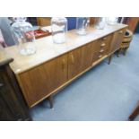 A G-PLAN TEAK SIDEBOARD, HAVING TWO-DOOR END CUPBOARDS, FOUR DRAWERS AND A DRINKS FALL-FRONT SECTION