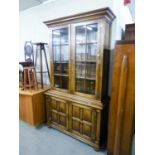 A GOOD QUALITY DISTRESSED OAK DISPLAY CABINET, THE LOWER SECTION HAVING TWO PANEL DOORS, THE UPPER