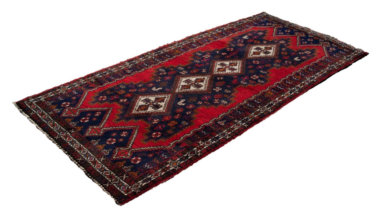LARGE SHIRAZ RUG WITH A CHAIN OF FOUR WHITE GROUND DIAMOND SHAPED CENTRE MEDALLIONS, on a black