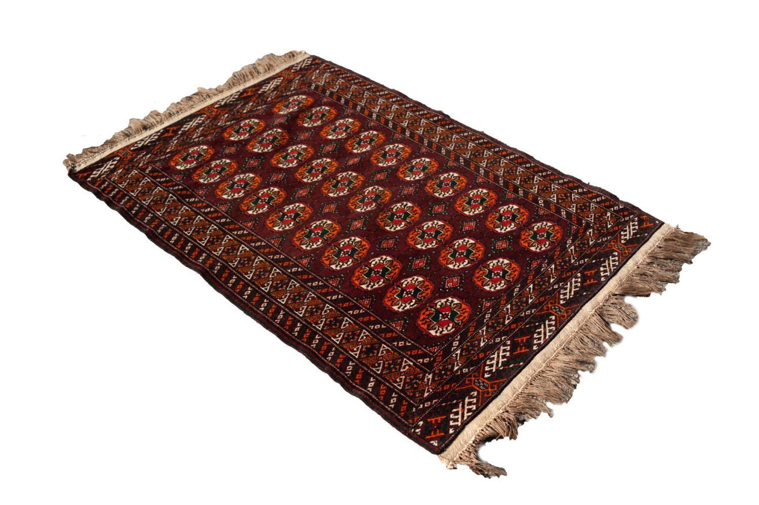 TURKOMAN BOKHARA WOOL RUG, with three rows of ten Herat Mauri primary guls on a dark wine red field,