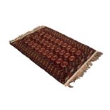 TURKOMAN BOKHARA WOOL RUG, with three rows of ten Herat Mauri primary guls on a dark wine red field,