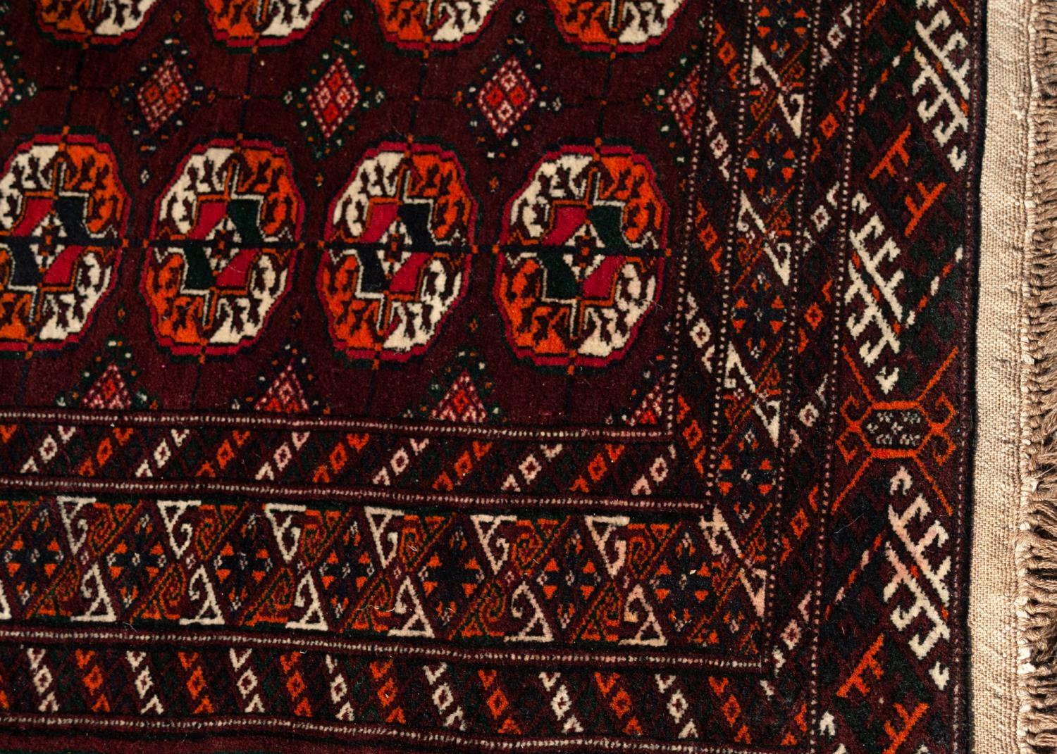 TURKOMAN BOKHARA WOOL RUG, with three rows of ten Herat Mauri primary guls on a dark wine red field, - Image 3 of 3