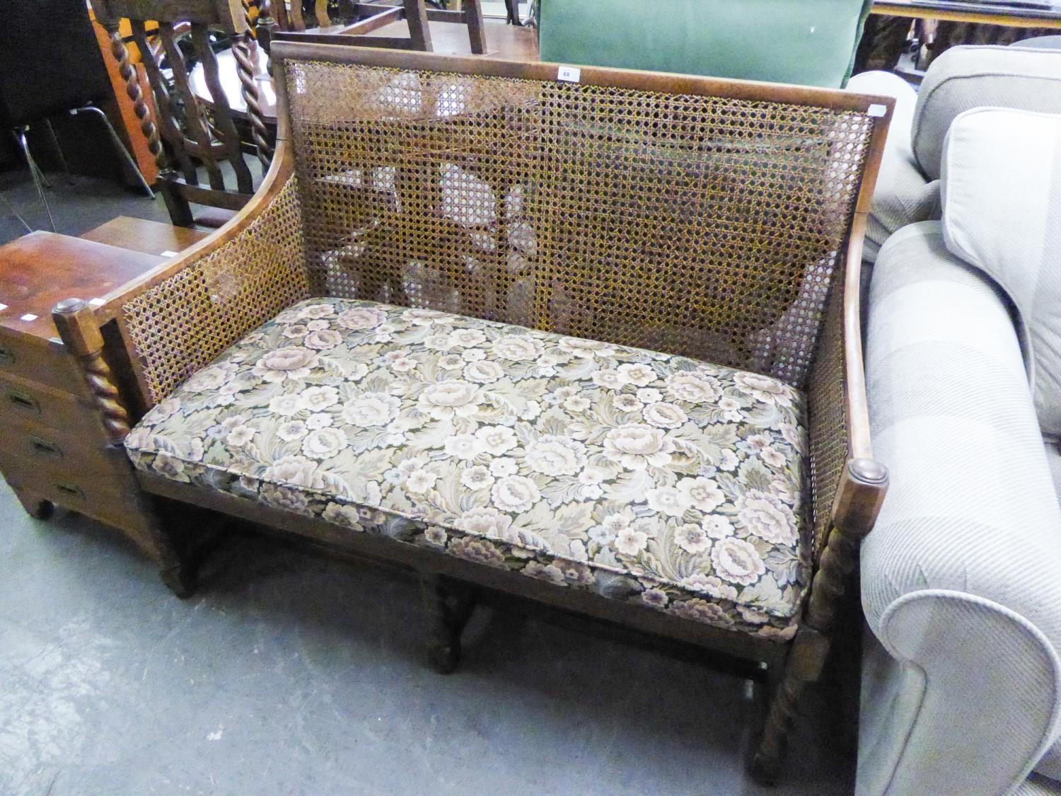 AN OAK TWO SEATER SETTEEE WITH WICKER BACK AND ARMS RAISED ON BARLEY TWIST SUPPROTS