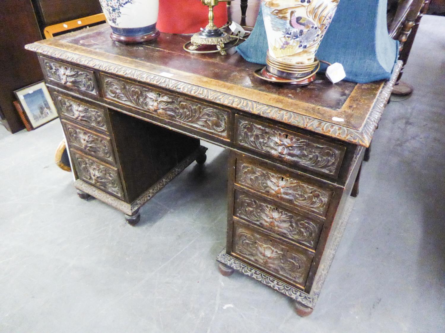 AN EARLY TWENTIETH CENTURY CARVED OAK KNEEHOLE PEDESTAL DESK