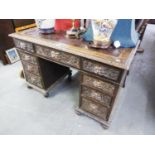 AN EARLY TWENTIETH CENTURY CARVED OAK KNEEHOLE PEDESTAL DESK