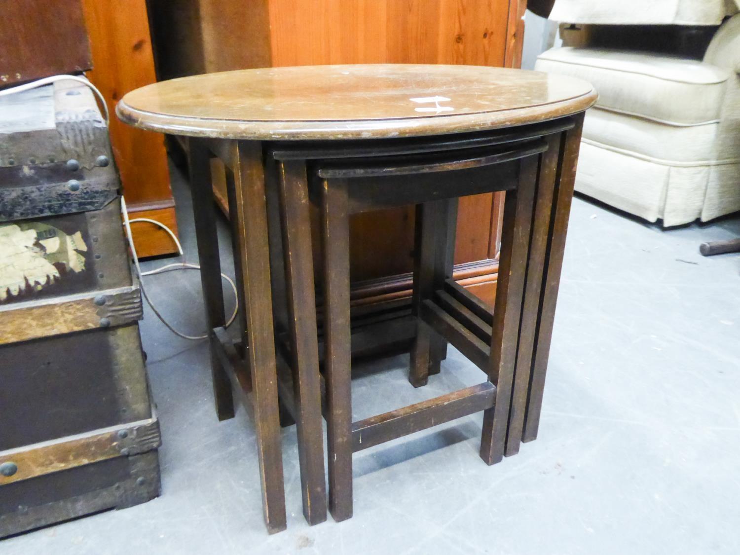 A WALNUT OVAL COFFEE TABLE ON STRAIGHT LEGS AND A NEST OF TWO OAK COFFEE TABLES (3)