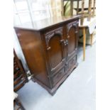 A JACOBEAN STYLE CARVED OAK TWO DOOR TELEVISION CABINET, WITH FALL FRONT COMPARTMENT BELOW,