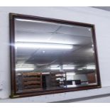 A LARGE BEVELLED EDGE WALL MIRROR IN MAHOGANY FRAME WITH BRASS CORNERS