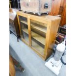 A LIGHT OAK SMALL BOOKCASE ENCLOSED BY TWO GLAZED DOORS, ENCLOSING TWO SHELVES, ON PLINTH BASE, 3’9”