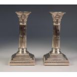 A PAIR OF EDWARDIAN WEIGHTED SILVER CORINTHIAN COLUMN CANDLESTICKS WITH REMOVABLE GADROONED NOZZLES