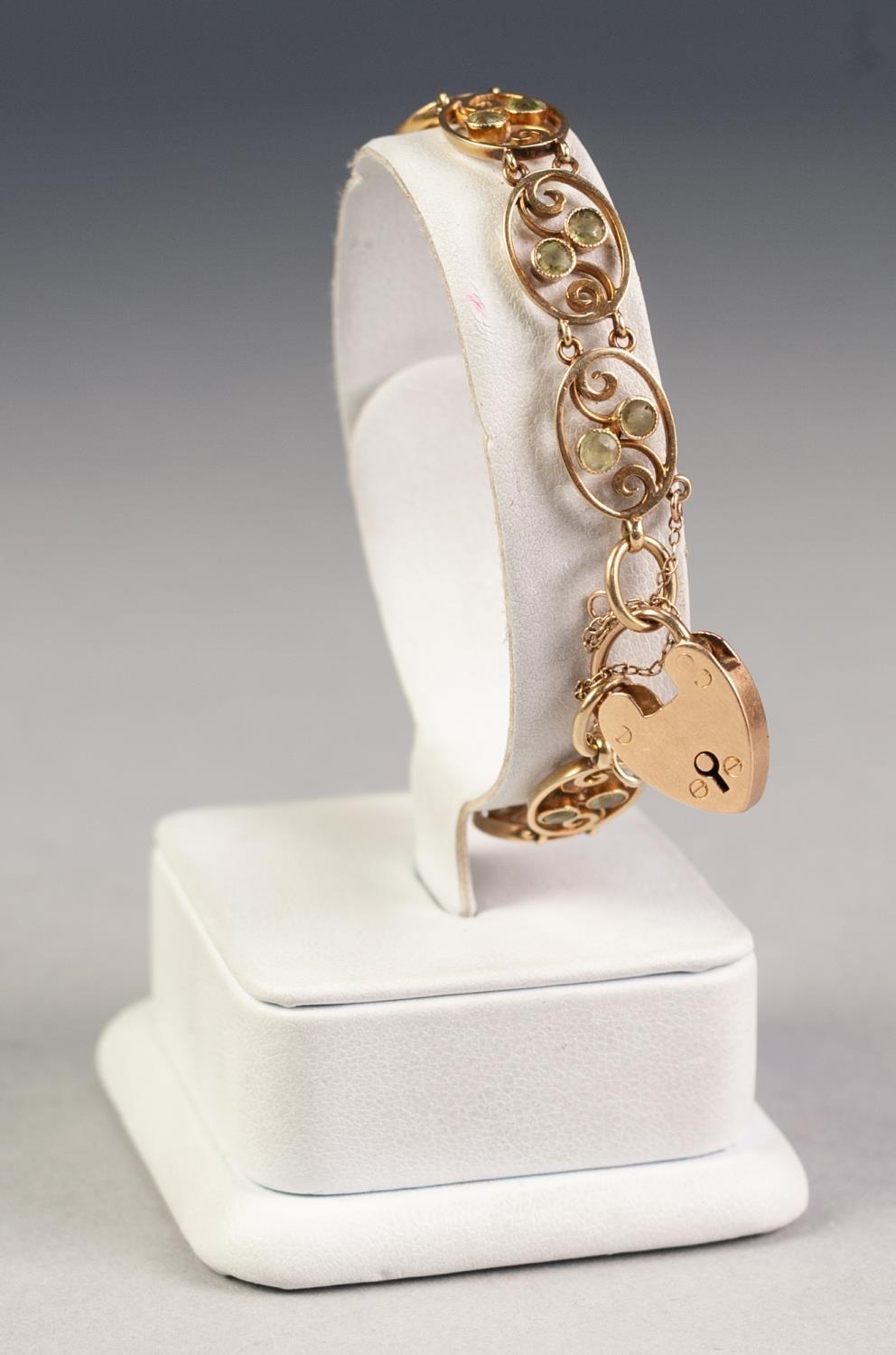 15ct GOLD BRACELET with ten openwork oval links each set with two small peridots and the 15ct GOLD