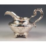 VICTORIAN SILVER CREAM JUG, repousse with floriated scrollwork centring vacant cartouche, leaf-