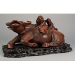 CHINESE LATE QING DYNASTY CARVED WOODEN RECUMBENT WATER BUFFALO with two figures on its back, on a