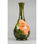 WALTER MOORCROFT HIBISCUS PATTERN TUBE LINED POTTERY VASE, of footed bottle form, painted in tones