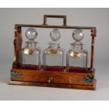 LATE NINETEENTH/ EARLY TWENTIETH CENTURY LOCKABLE OAK THREE BOTTLE TANTALUS, with electroplated