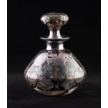 AN EARLY 20TH CENTURY CLEAR GLASS WHITE METAL OVERLAID PERFUME BOTTLE WITH CONFORMING STOPPER