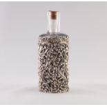 AN EDWARDIAN GLASS SCENT BOTTLE WITHIN A STAMPED SILVER MOUNT, of openwork foliate scrollwork and