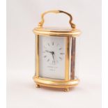 LATE 20th CENTURY ENGLISH OVAL GORGE CASED BRASS CARRIAGE CLOCK, the white enamel dial marked '