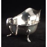 A MODERN SILVER SAUCE BOAT, with everted cut rim, plain loop handle, standing on three pad feet,