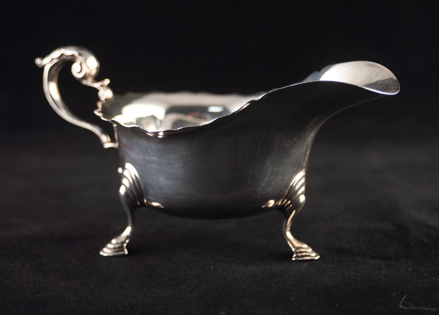 A TWENTIETH CENTURY SILVER SAUCE BOAT with everted cut rim, leaf capped scroll handle, standing on - Image 2 of 3