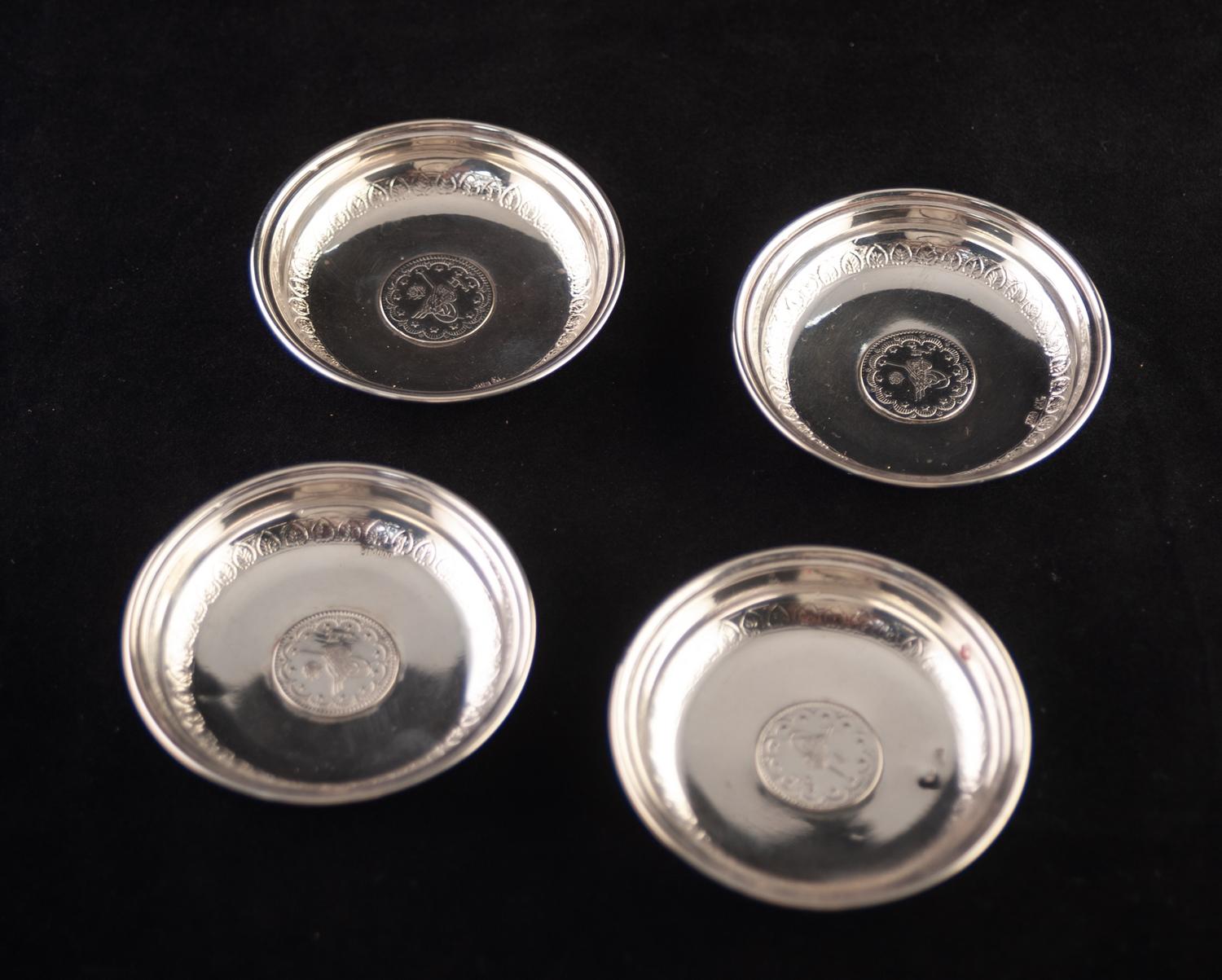 A SET OF FOUR .800 STANDARD CONTINENTAL SMALL CIRCULAR ASHTRAYS, each with a coin inset base, 3" (