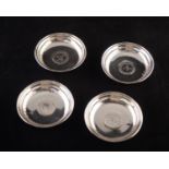 A SET OF FOUR .800 STANDARD CONTINENTAL SMALL CIRCULAR ASHTRAYS, each with a coin inset base, 3" (