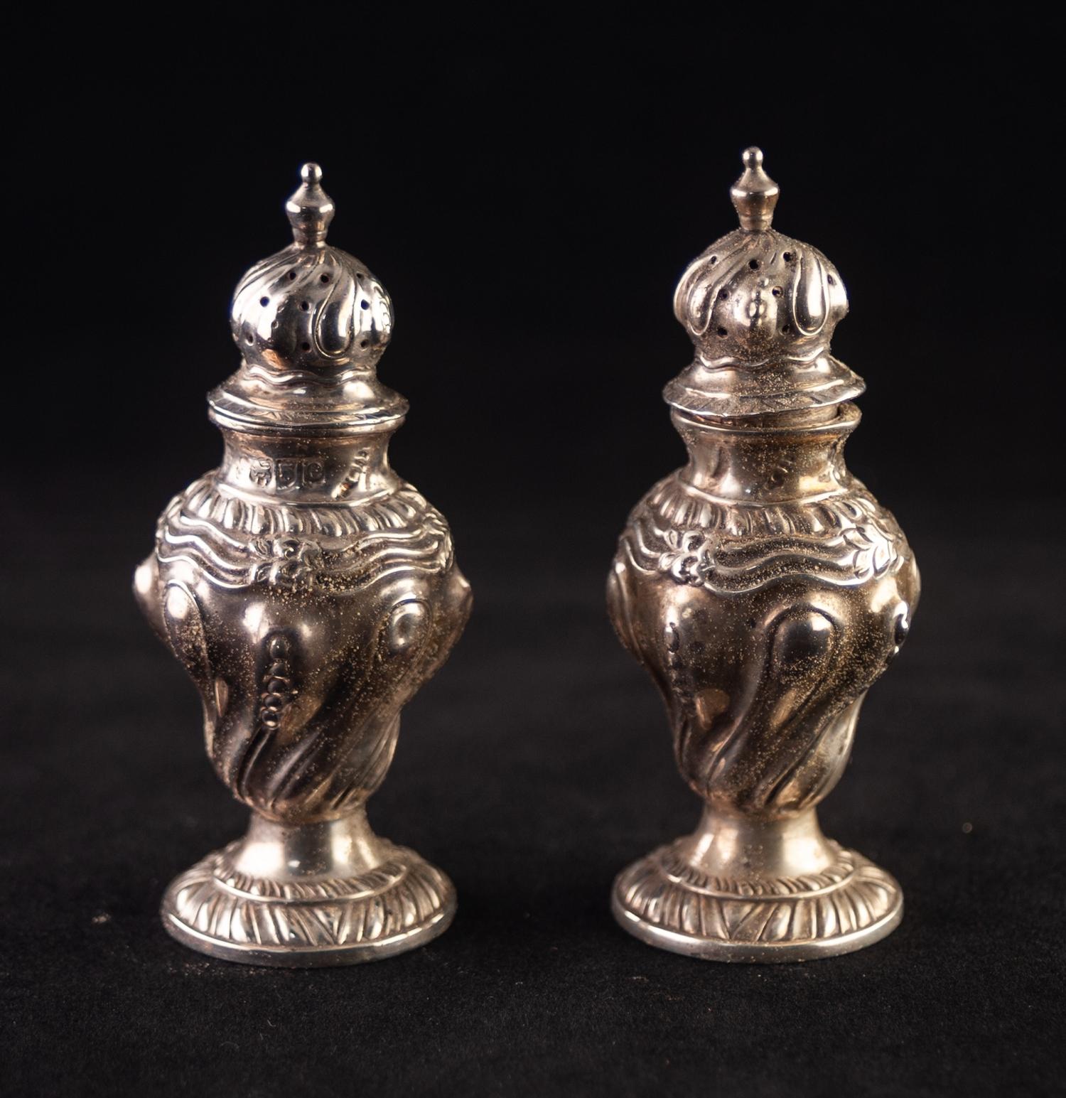 A PAIR OF LATE VICTORIAN SILVER PEPPERETTES, of rococo revival wrythen lobated repousse decorated