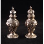 A PAIR OF LATE VICTORIAN SILVER PEPPERETTES, of rococo revival wrythen lobated repousse decorated
