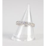 WHITE METAL RING COLLET SET WITH A ROW OF SEVEN SMALL DIAMONDS GRADUATING FROM THE CENTRE, 3.6gms,